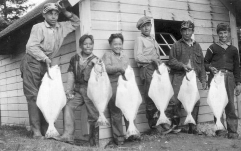 Kids lined up holding halibut